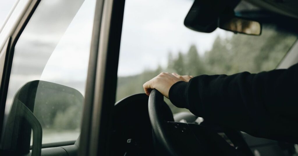 Motorista com a mão no volante, dirigindo com calma — CNH suspensa, o que fazer