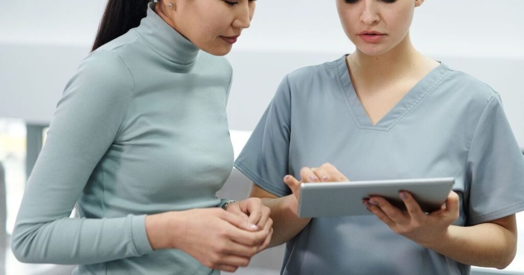 Duas profissionais de saúde analisando informações em um tablet na gestão de uma clínica