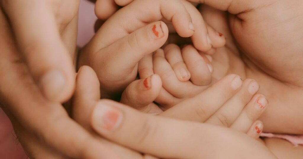 Mãos de adultos segurando as mãos de uma criança