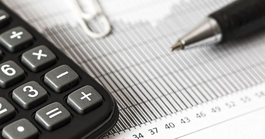 Calculadora e caneta sobre documentos com números