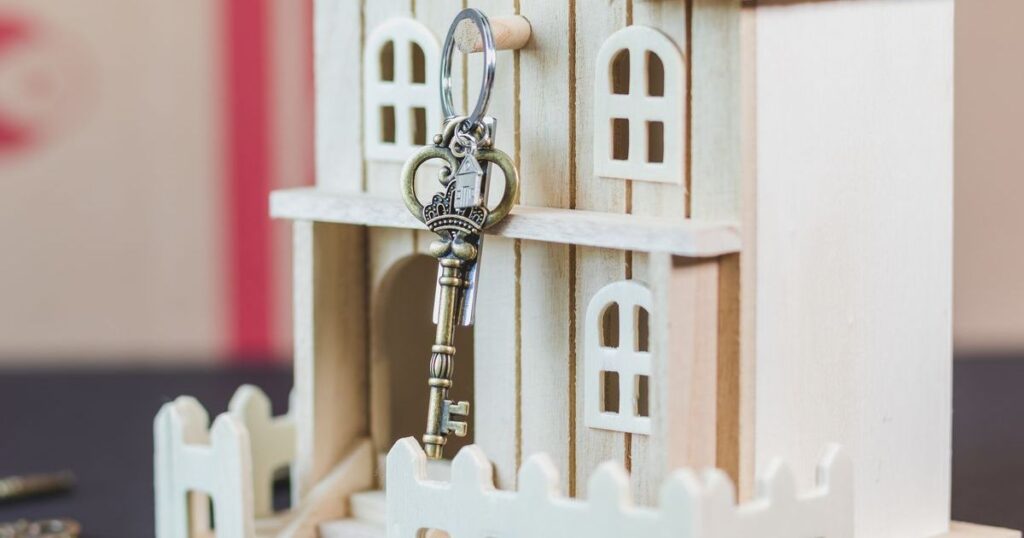 Chave sobre uma miniatura de casa de madeira, representando a parte de um imóvel na herança