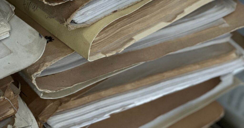 Pilha de pastas e documentos antigos guardados, representando o bem esquecido que aparece depois do inventário