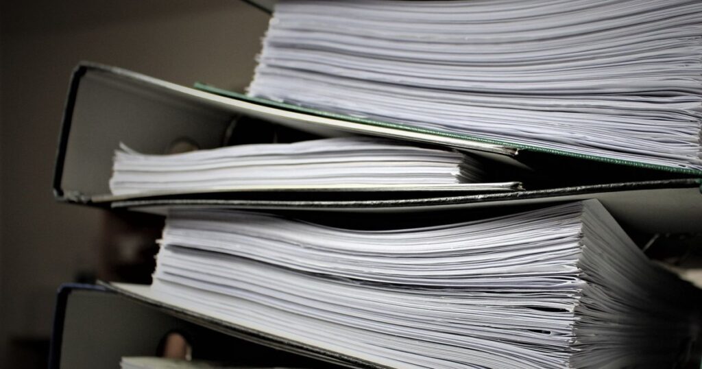 Pastas de arquivo abarrotadas de documentos, empilhadas como os autos de uma execução de dívida bancária da empresa