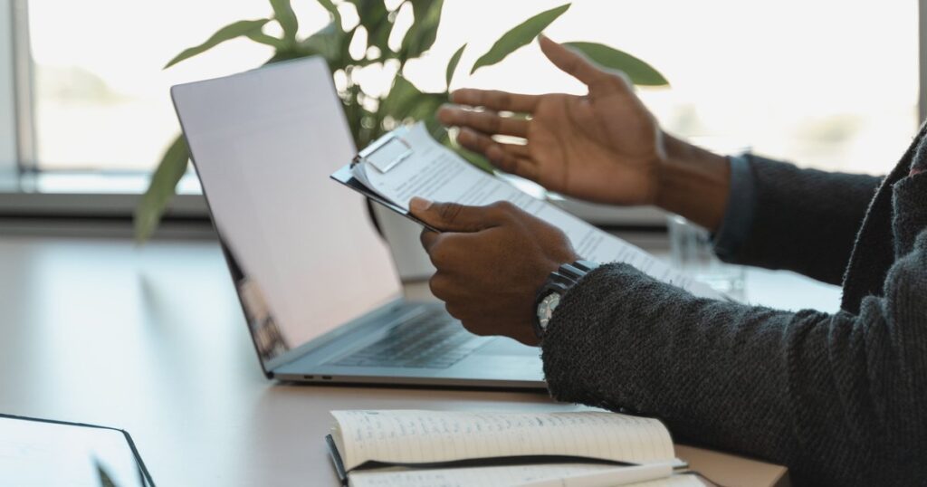 Renegociar dívida da empresa no Banco do Brasil: empresário com a proposta impressa na mão, ao lado do notebook, antes de responder ao banco