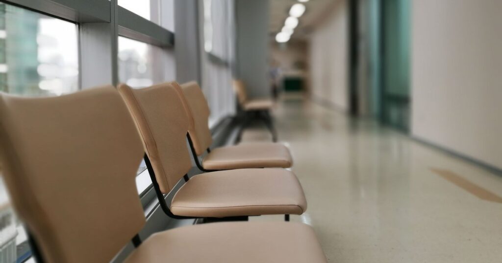 Cadeiras de espera vazias no corredor de um hospital, cenário do atendimento de urgência recusado por carência do plano de saúde